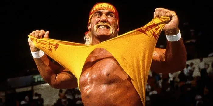 Hulk Hogan với phong thái biểu tượng trên sàn đấu, ánh đèn sân khấu chiếu rọi, đại diện cho di sản phức tạp của một huyền thoại WWE.