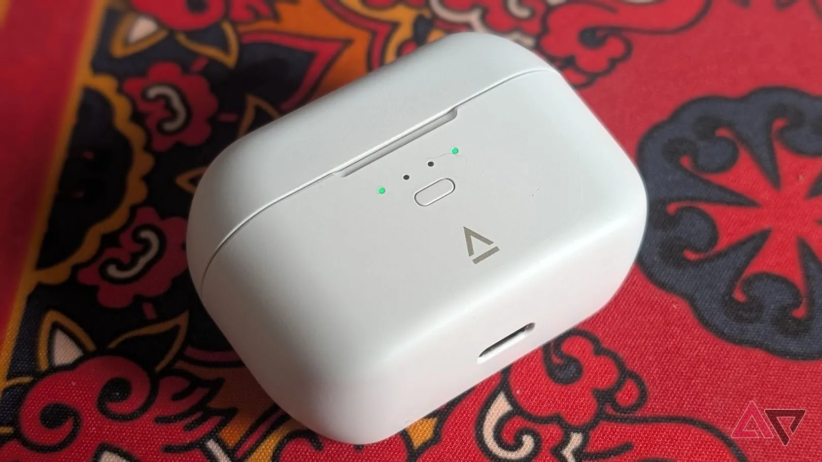 Hộp và case tai nghe Creative màu trắng đặt trên nền đỏ họa tiết