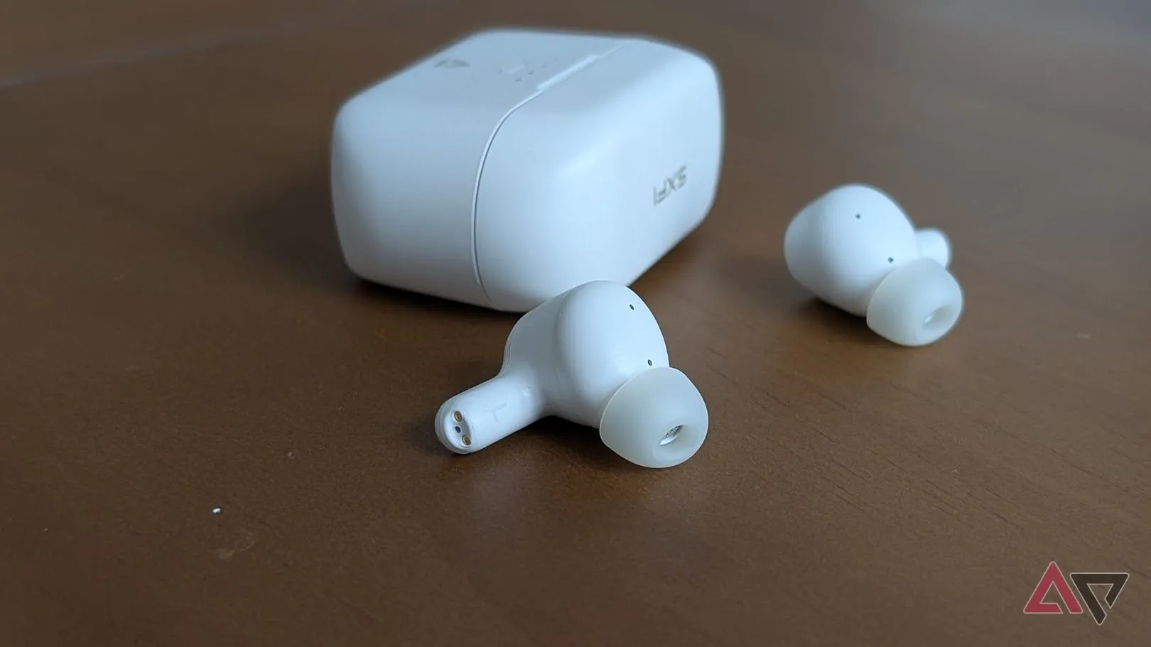 Tai nghe Creative màu trắng đặt trên bề mặt gỗ, nhấn mạnh thiết kế in-ear cho âm thanh vòm