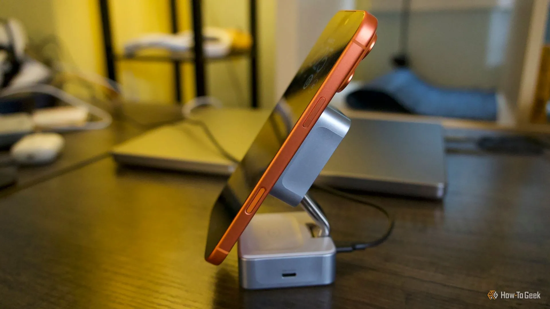 Ugreen MagFlow đặt ngang với iPhone 17 Pro Max màu cam trên đế sạc đứng